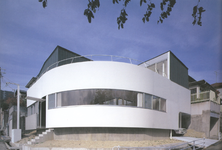 1/4 Circle House TThe project site is set on a slope with privileged view of Rokko-mountain and Osaka-bay. 9mm steel sheet with 20m in length takes the shape of a quarter circle with a radius of 6m, and the continuous wide window provides a panoramic view. This column-less continuous window was achieved by freeing the wall from the structure. <br />The entrance hall and the courtyard are paved using the same material, enhancing the spatial continuity of the space. The panoramic view is available not only from the indoor space but also from the courtyard. The courtyard is located at the center of the building so that circulation flows round the void. It also works as environmental device, which maintains the natural lighting and the ventilation. <br />This house accommodates a young married couple with a parent. They can share the panoramic view from the common living room and the kitchen, while the courtyard keeps them apart efficiently where privacy is required.<br />I intended to maintain the privacy and utility while trying to enhance the relationship between human and natural environment, which is an eternal task of urban living. <br />