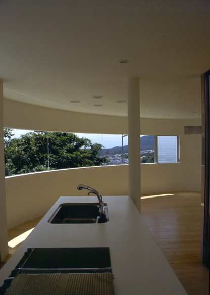 1/4 Circle House TThe project site is set on a slope with privileged view of Rokko-mountain and Osaka-bay. 9mm steel sheet with 20m in length takes the shape of a quarter circle with a radius of 6m, and the continuous wide window provides a panoramic view. This column-less continuous window was achieved by freeing the wall from the structure. <br />The entrance hall and the courtyard are paved using the same material, enhancing the spatial continuity of the space. The panoramic view is available not only from the indoor space but also from the courtyard. The courtyard is located at the center of the building so that circulation flows round the void. It also works as environmental device, which maintains the natural lighting and the ventilation. <br />This house accommodates a young married couple with a parent. They can share the panoramic view from the common living room and the kitchen, while the courtyard keeps them apart efficiently where privacy is required.<br />I intended to maintain the privacy and utility while trying to enhance the relationship between human and natural environment, which is an eternal task of urban living. <br />