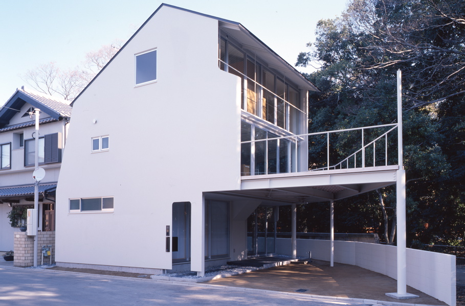 Ni House This house is built on a small triangular site adjacent to the sacred forest of the shrine. It opens toward the forest on the south and east side while it closes its main and north facades with the steel sheet with few small ventilation windows to maintain the residents’ privacy. <br />The living room and kitchen are located along the terrace on the first floor so that they can enjoy the scenery of the forest. The whole house is organized around the staircase that visually connects the upper floors and lower floor. A private room and a doma entrance (an entrance situated at the same level as the ground) comprising an atelier are located on the ground floor, and additional private rooms are located on the second floor.<br />The building is constructed in conventional steel structure with facades composed of U-shaped steel sheet with a thickness of 9mm, and aluminum double-glazed sash windows. The thicknesses of external walls are 100mm including the insulation. It is a very effective method for maximizing the usable floor area especially when the building is small. I believe it is a reliable choice considering the durability and the heat retention abilities. <br />As a cladding material, 9mm steel sheet has more than enough durability. Naturally enough, as the steel sheet becomes thinner, it becomes lighter and easy to manipulate, however, it becomes unreliable for cladding material as it no longer provides adequate corrosion resistance and heat retention. Additionally, It will be less cost-effective as it requires more complicated processing operation to turn into panels. The selection of steel thickness requires deliberation even if you put aside the durability. Constructing building with steel sheet cladding requires some time processing in factory but it is still an efficient method, as it requires less operation on site.<br />