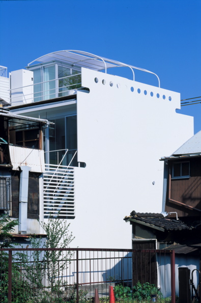 Mo House This house is situated in relatively high-density urban context consisting mixed residential/commercial use. It sits on a narrow site measuring approximately 59m2. The shop on the ground floor is visually connected to the courtyard at the rear. The residential part is situated on the upper floor. <br />I have taken in account the geographic feature of Kobe when designing this house. North and South façades are double-glazed, providing the views of mountain and sea. These openings and the courtyard efficiently provide the natural lighting and the ventilation into the internal space. Private areas are placed on the first floor and the living room is located on the second floor. The layout is carefully considered so that spatial volume and the brightness increase as one proceeds to the higher floor. The roof top terrace comprises sanitary space and it acts as the sky garden that offers the view of sky, mountain and sea.<br />The reason I’m attracted to steel as building material is for its unlimited possibilities. I’m convinced that it goes beyond the structural limitation that has been established during the modernist age. In addition to its structural durability, I also consider steel as a high quality external cladding material.<br />I chose to use 9mm steel sheet not only for its texture and durability but also for the impression it can give of being thin. I believe the texture of steel, like the texture of thick stone in Mies’s architecture, can create the impression of reliability and sophistication.<br />For instance, a car needs to be light and durable, but texture of thin steel sheet wrapped around it is never considered as important as it is in architecture. The application of steel in architecture is not only about the manufacturing process in factory. The thinness of the material changes according to the size of the space and it will affect the impression and the texture. The reason I’m being particular about the texture is because architecture is not merely used, but also is lived in.<br />