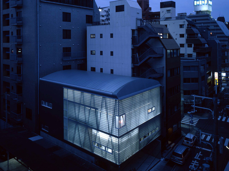 神戸質屋会館 建物の主用途は、会議及び事務室、質屋組合員専用の、競り会場である。競り会場は、敷地一杯の面積が要求されたため、斜柱と円弧のクロス梁を組み合わせ、大無柱空間を構成、意匠した。１階はＲＣ壁、そして２、３階は、ガラスブロックとスチールシートで外装を仕上げた。都市建築における表情の変化を演出するため、半透明で均質採光に有効なガラスブロックを使用した。内部には、様々な色及び透明性を持つガラスの間仕切りを使用し、鉄、石、木の組み合わせと共に、色々な視覚的変化をもたらした。