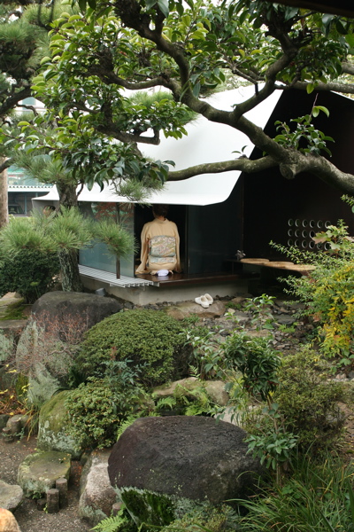 Steel Sheet Teahouse The engawa (veranda) in this minka faces the remnants of a precious Japanese-style garden, which was maintained for many years as a hobby of the preceding generation. Inheriting the shape of this bequest, a contemporary monocoque tearoom was newly installed in the garden. So as not to hurt the existing delicate garden trees, the main body of the tearoom was made in a factory, then simply placed in its location in the garden. Overall, it is divided into a half-exterior meeting part and a stoic interior space comprising an alcove and two tatami mats, covered with a roof membrane of steel sheet. An extraordinary space, this tearoom is a contemporary meditation space, and at the seasons change it is a place in dialogue with nature. As well as being also to wander through the exciting garden, visually there emerges a spatial continuity that unifies inside and outside even more than the engawa, producing a lifestyle in intimate contact with nature.<br /><br />The steel sheet that I used goes from an architectural building frame to an industrially processed product like a vehicle, and the sculptural usage avoids the impact of the strong expression of steel. The advantage of this material is its high degree of strength and the possibility of high-precision factory fabrication through using CAD; a standard quality may be maintained everywhere, the price-per-weight does not vary much, and it can cope with customization and prefabrication. The sizes for this tearoom were determined by the volume of heights and widths that are able to be transported by vehicle. It was all produced at the factory, and the 9mm-thick steel sheets were bent into curved surface at key points in order to make a unified pre-strengthened structure. Divided into two parts, it was then lowered as-it into the garden by crane. It was then reconnected, fittings were inserted, tatami mats were laid, and this was all completed over a short period of time. The inside and outside have been given a different expression. Traces of the fabrication process and welding have been left in the interior, and the outside is finished with industrial smooth painting like a vehicle, with a taste for simplicity and quiet.