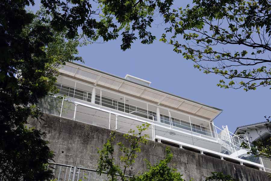 Open Terrace The main characteristics of this house are the deck terraces that open towards the forest. All three floors have large openings and terraces facing the forest on the east side. The overhang on the first floor is made of wooden louvers and glass so that light can reach the lower terrace. In contrast, the entrance hall and “doma” space (space situated at the same level as the ground) on the west side have only few small openings or lattice-windows to keep that part enclosed. This house is a harmonization between openness and calmness. 