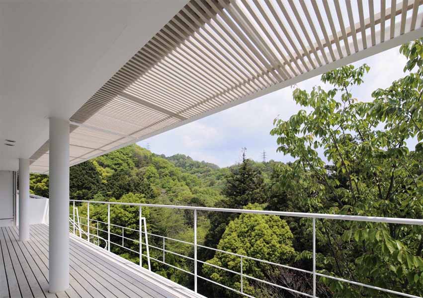 Open Terrace The main characteristics of this house are the deck terraces that open towards the forest. All three floors have large openings and terraces facing the forest on the east side. The overhang on the first floor is made of wooden louvers and glass so that light can reach the lower terrace. In contrast, the entrance hall and “doma” space (space situated at the same level as the ground) on the west side have only few small openings or lattice-windows to keep that part enclosed. This house is a harmonization between openness and calmness. 